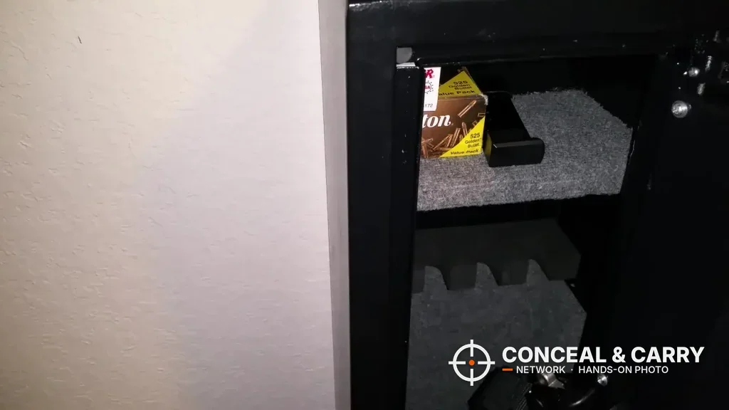 Carpeted shelf with a box of ammunition inside the Barska rifle safe