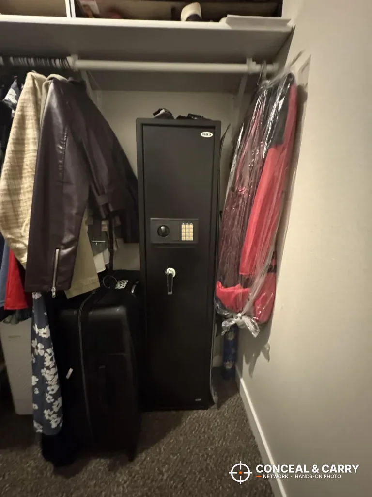BBRKIN rifle safe standing in a walk-in closet between hanging clothes