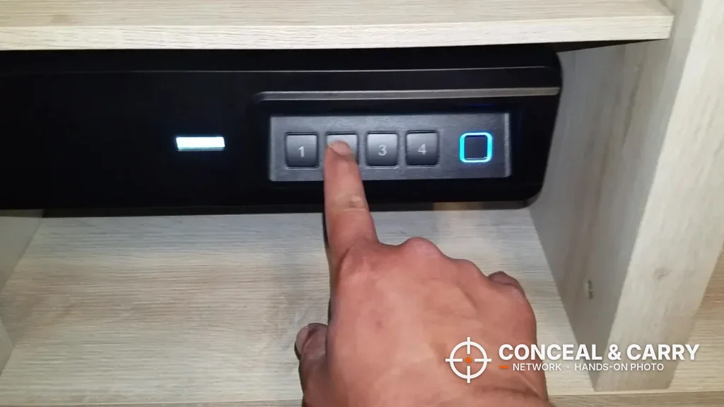 Finger pressing the keypad of a BBRKIN Slide-Away safe mounted under a shelf