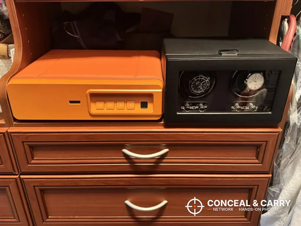Orange BBRKIN Slide-Away safe on a dresser beside a watch box