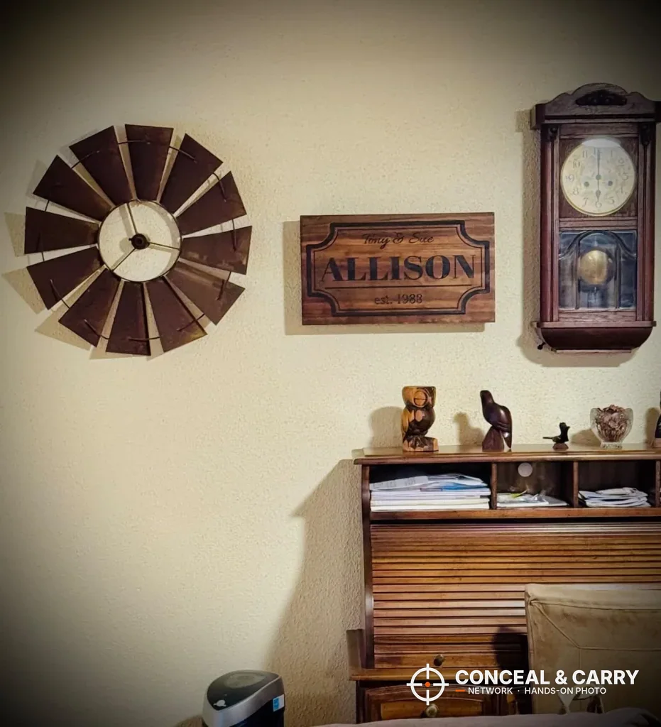 Bellewood hidden gun safe sign hung on a wall between two clocks above a desk