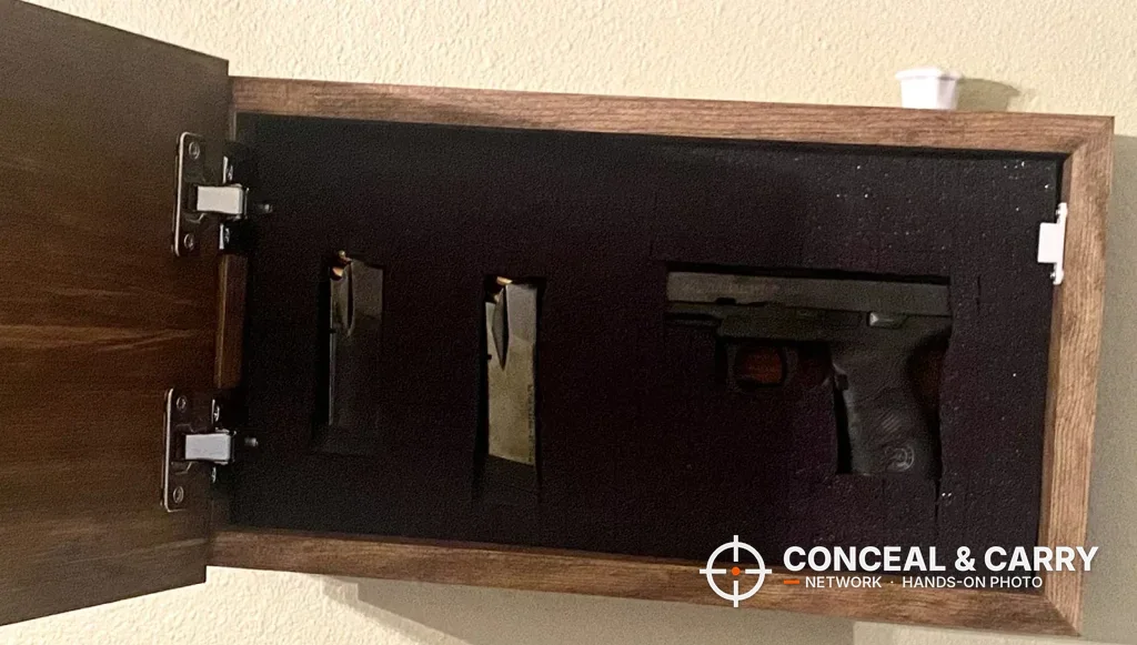 Bellewood hidden gun safe sign open on the wall with a pistol and two magazines in the foam