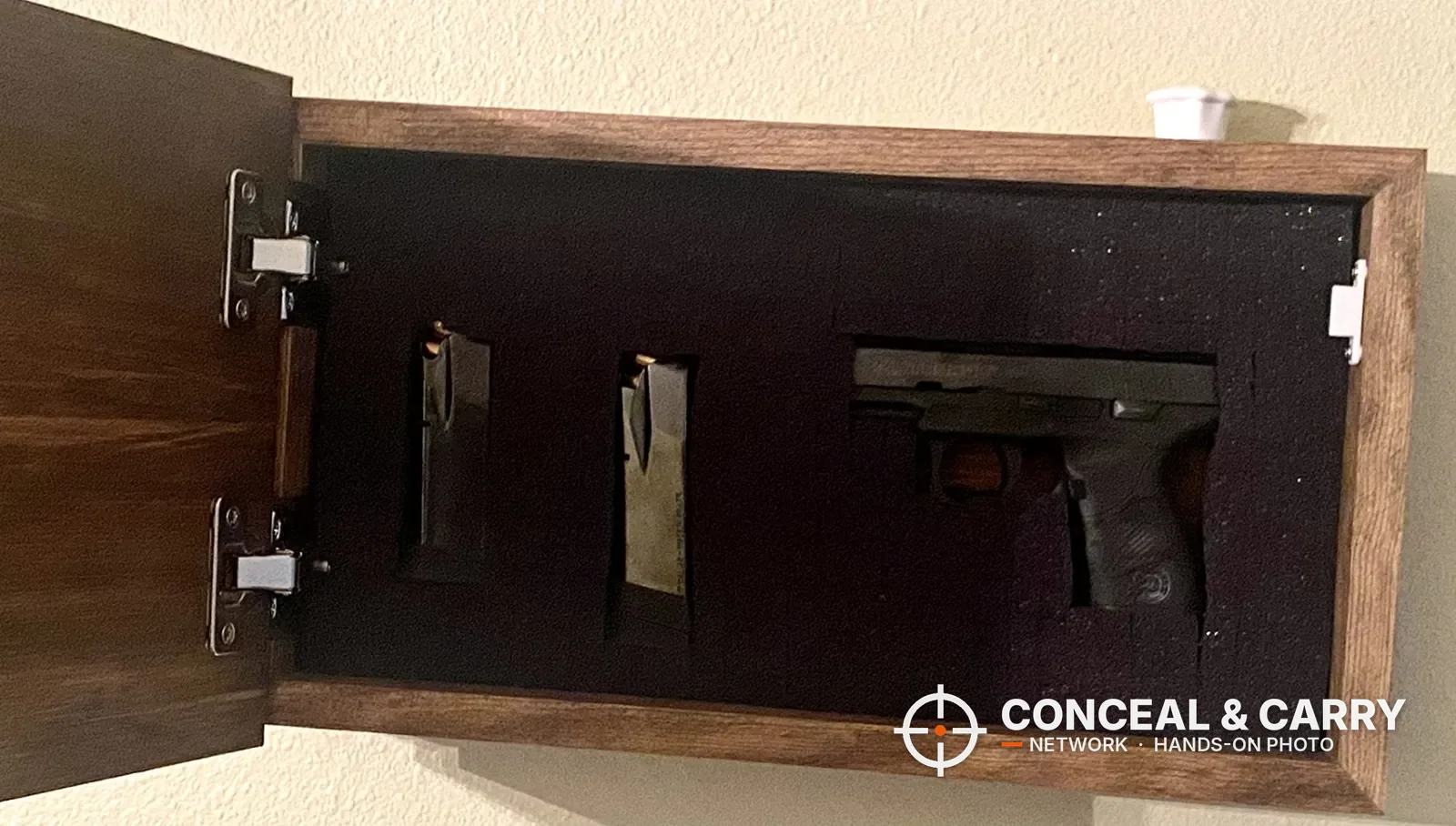 Bellewood hidden gun safe sign open on the wall with a pistol and two magazines in the foam