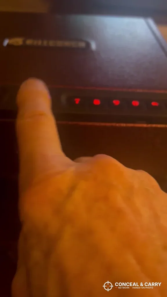 Finger at the BILLCONCH safe front panel with the red lights on