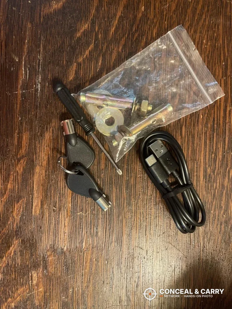 Billconch multi-pistol safe keys, hardware bag and USB cable laid out on a table