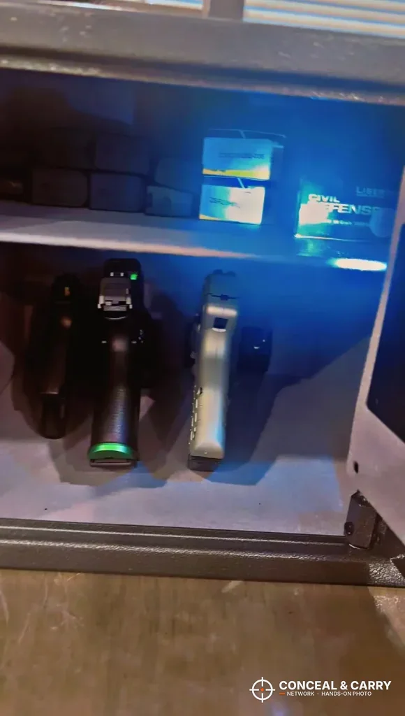 Two handguns hung on the Billconch multi-pistol safe bracket under a blue interior light