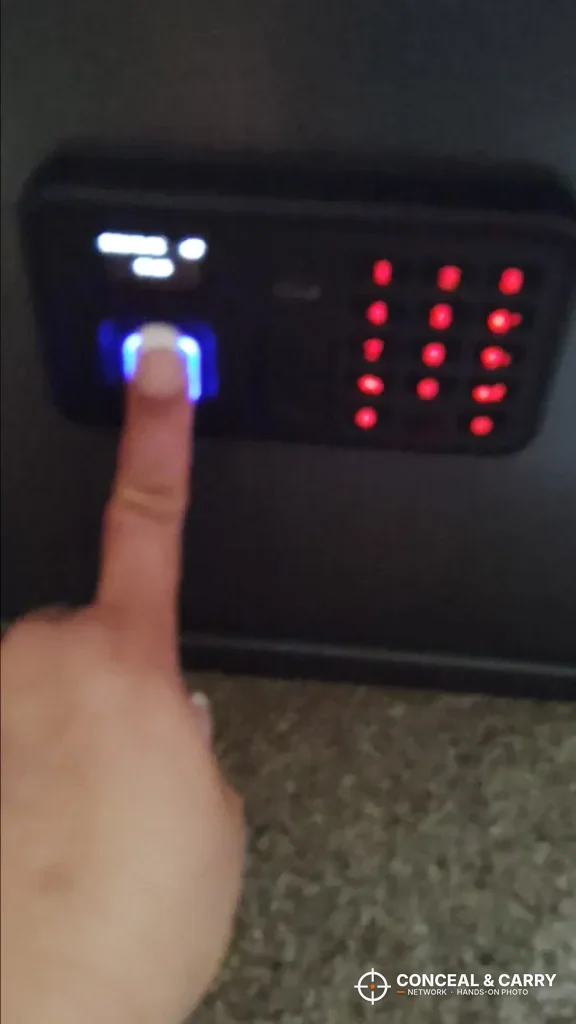 Finger on the Billconch multi-pistol safe fingerprint reader with the keypad lit red