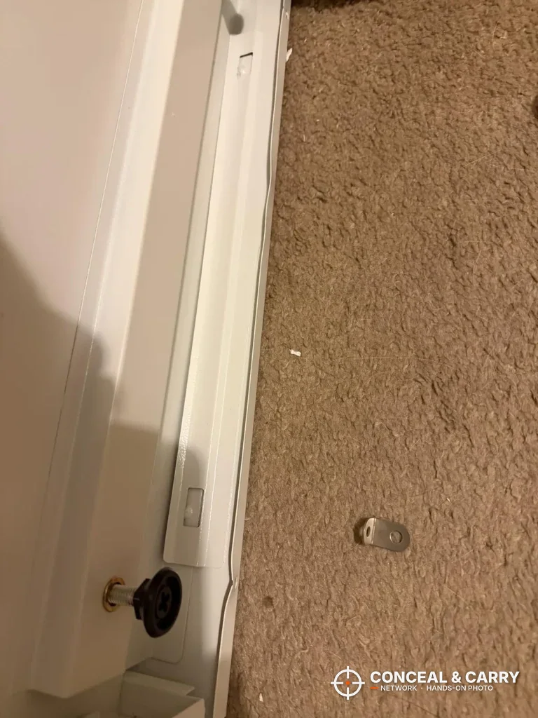 Floor-level view with a small loose part on the carpet beside the Bonusall safe