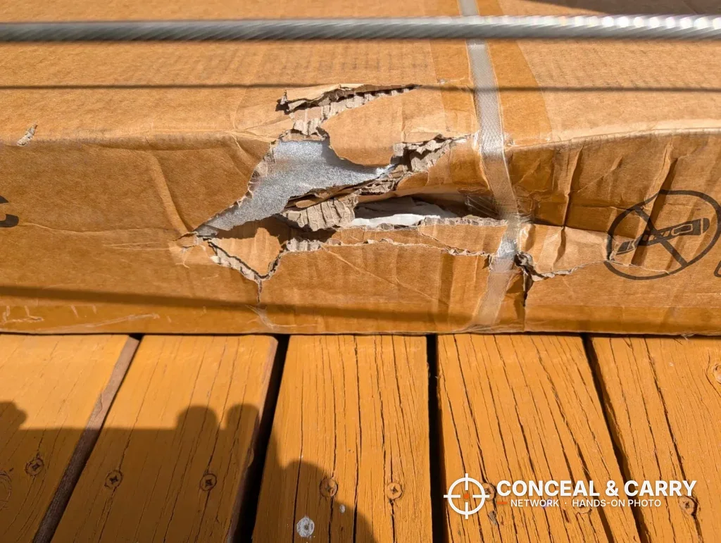 Torn side of a Bonusall gun safe shipping carton on a wooden deck