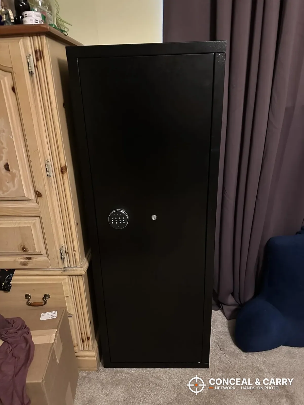 Bonusall 12-15 gun rifle safe standing closed in a bedroom, black finish with round keypad