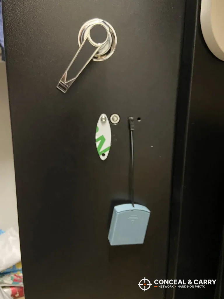 Chrome lever handle with tags hanging on the black Bonusall gun safe door