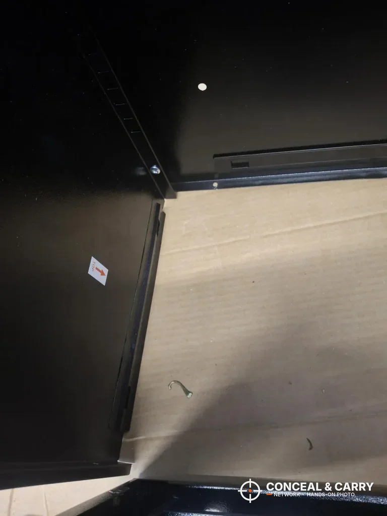 Inside corner of the black Bonusall 12-15 gun safe cabinet over cardboard