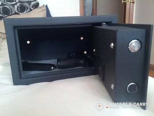 Bulldog BD1050 digital pistol vault open with a handgun on the carpeted floor