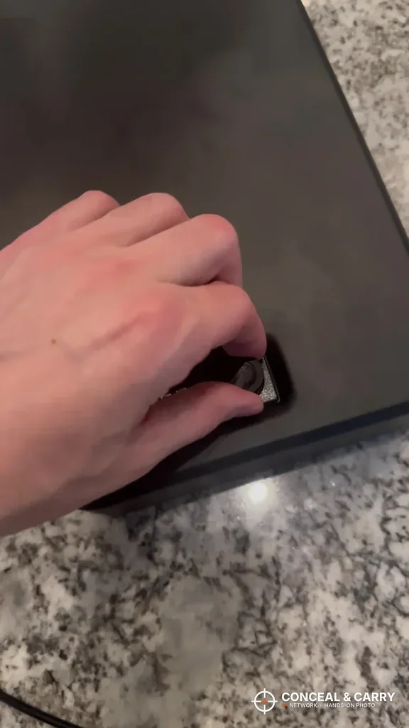 Hand at the latch of the closed Dalmbox pistol lock box on a countertop