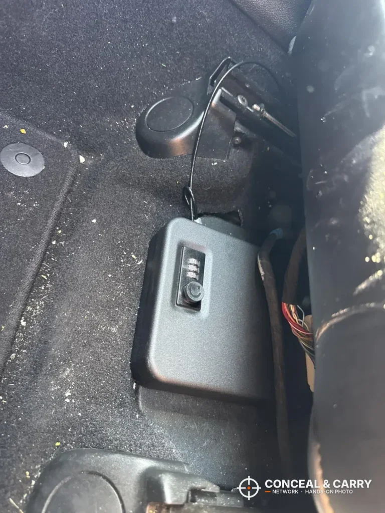 Dalmbox lock box on a car floor with the cable run up to the seat