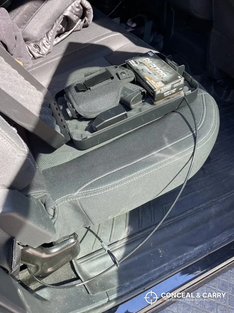 Dalmbox lock box open on a car seat with its cable looped down to the frame