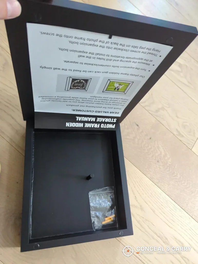 Dononr frame open with the manual in the lid and a hardware bag in the compartment