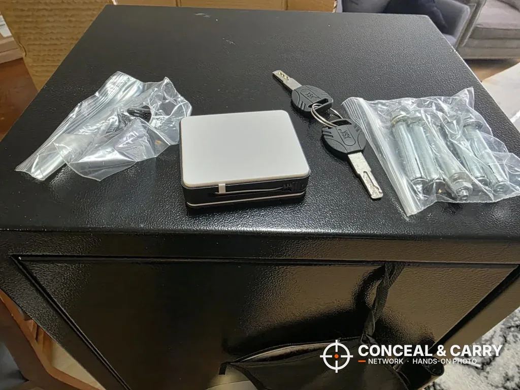 Keys, battery box and bags of bolts laid on top of the EMAXEE gun cabinet