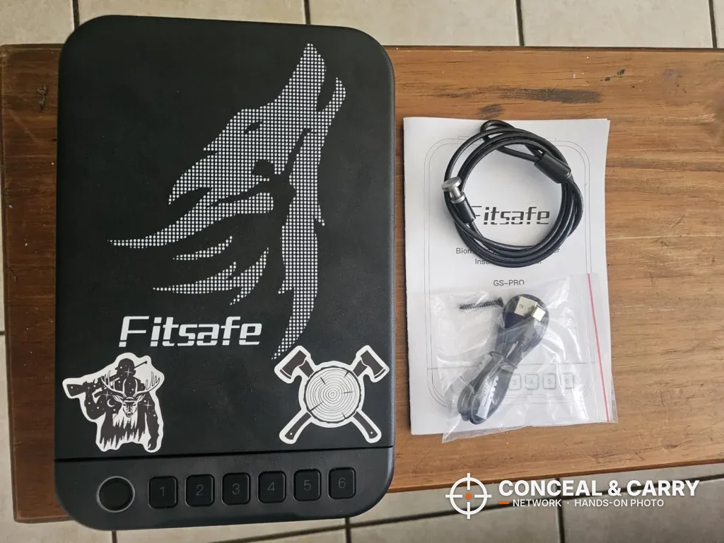 Fitsafe biometric safe beside its coiled security cable and paperwork