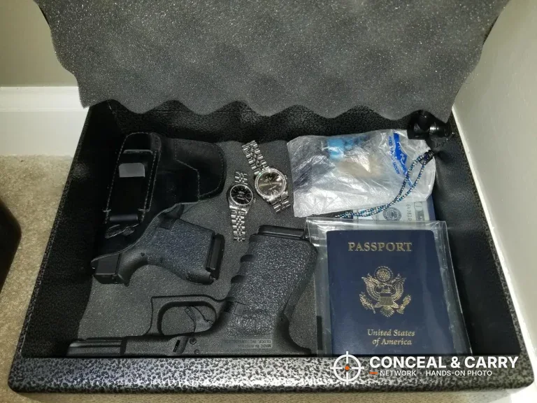 Fort Knox PB1 pistol box open with a holstered pistol, a watch and a passport inside