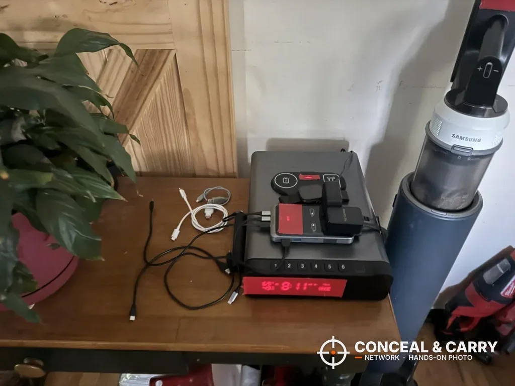 FTOP clock gun safe on a side table with devices on top and the clock display lit