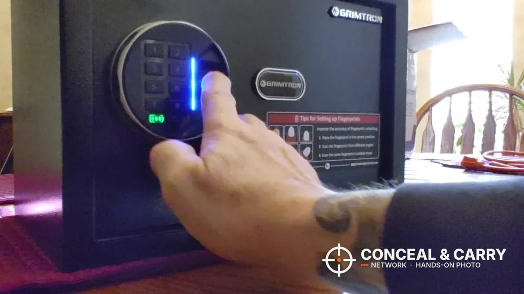 Finger on the Grimtron 4-pistol safe fingerprint reader with the blue light lit