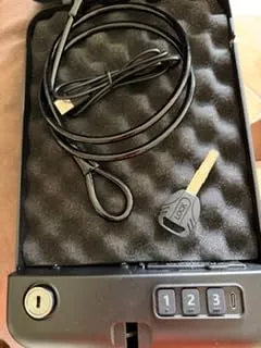 Grimtron car gun safe open with the security cable, USB cable and key on the foam