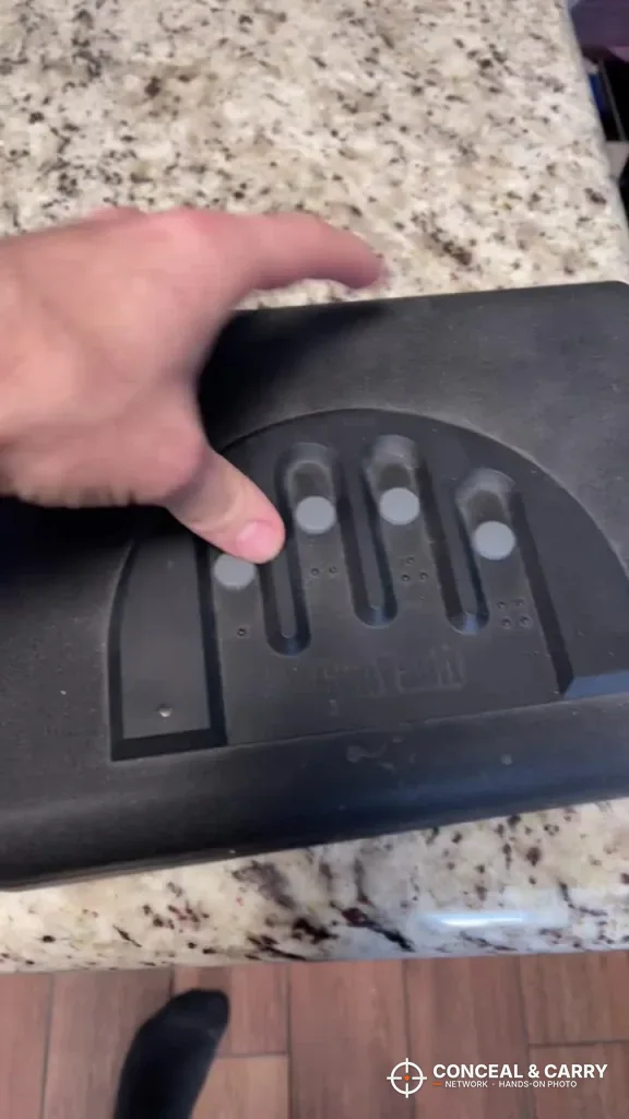Fingers resting on the GunVault MV500 keypad buttons