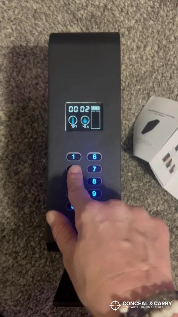 Finger pressing the blue-lit keypad on the HOLEWOR slider safe
