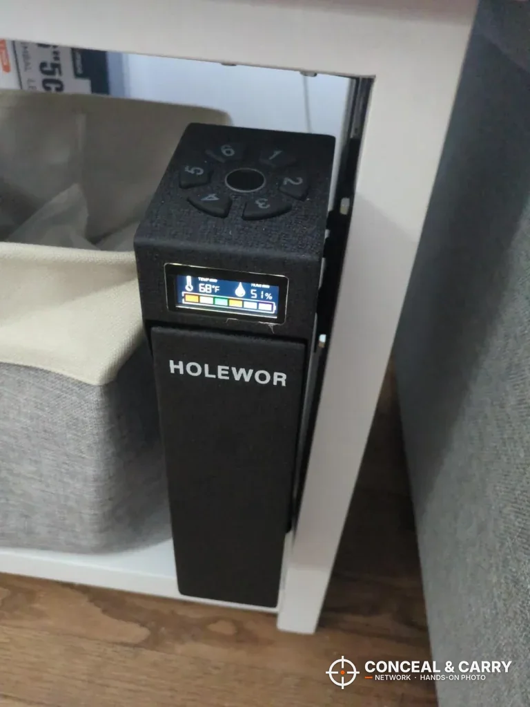 HOLEWOR drop-down safe mounted on the side of a nightstand with the display lit