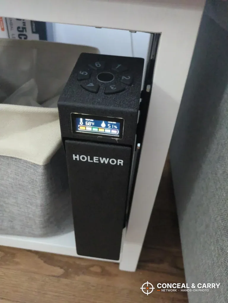HOLEWOR drop-down safe mounted on the side of a nightstand with the display lit