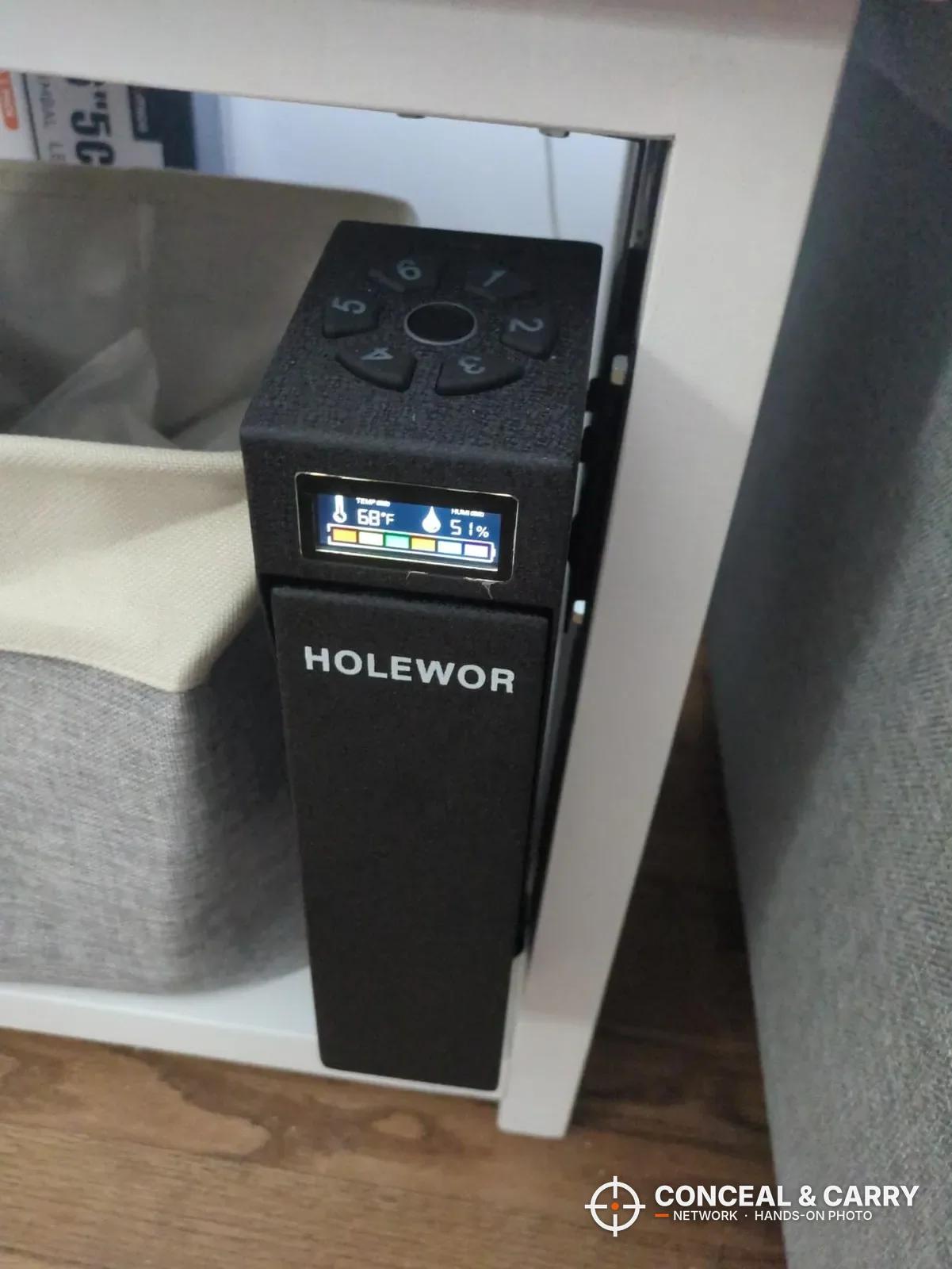 HOLEWOR drop-down safe mounted on the side of a nightstand with the display lit