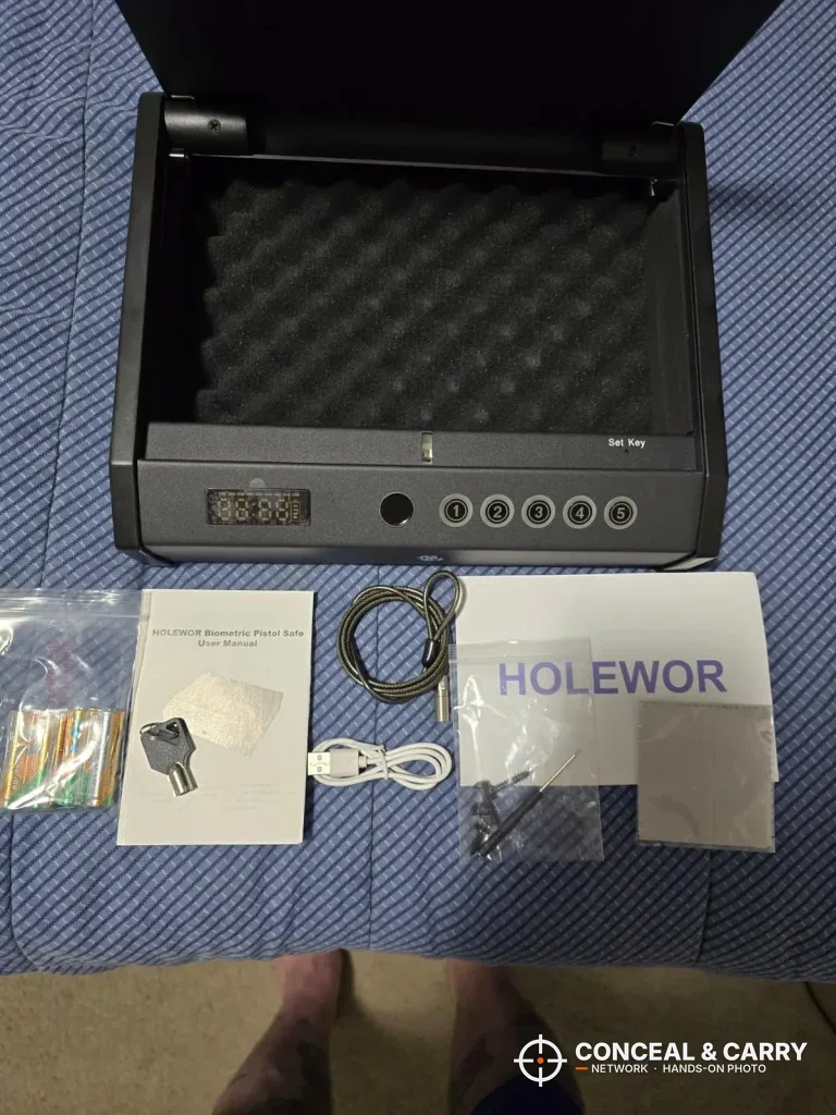 HOLEWOR handheld safe with keys, cable, USB cable and paperwork laid out in front of it