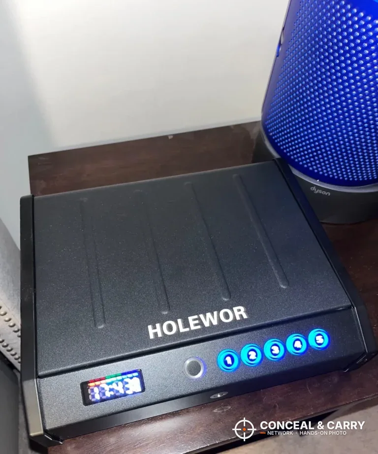 HOLEWOR handheld biometric safe closed on a nightstand with the display and buttons lit