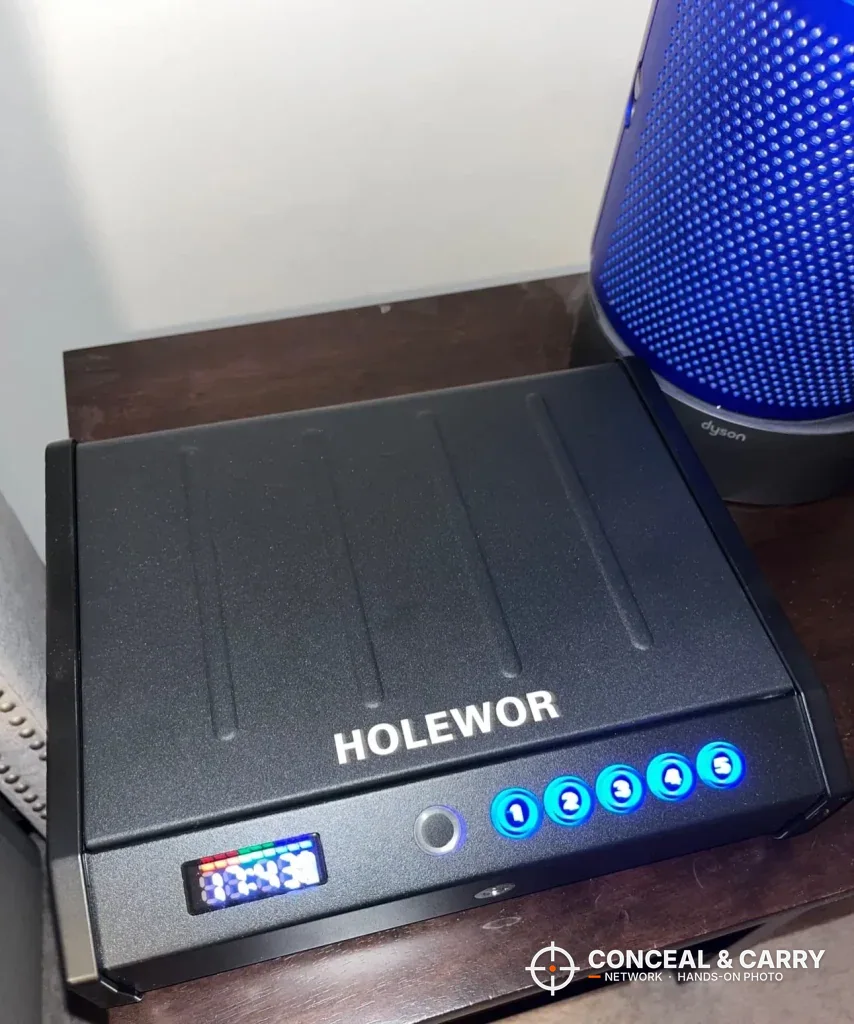 HOLEWOR handheld biometric safe closed on a nightstand with the display and buttons lit
