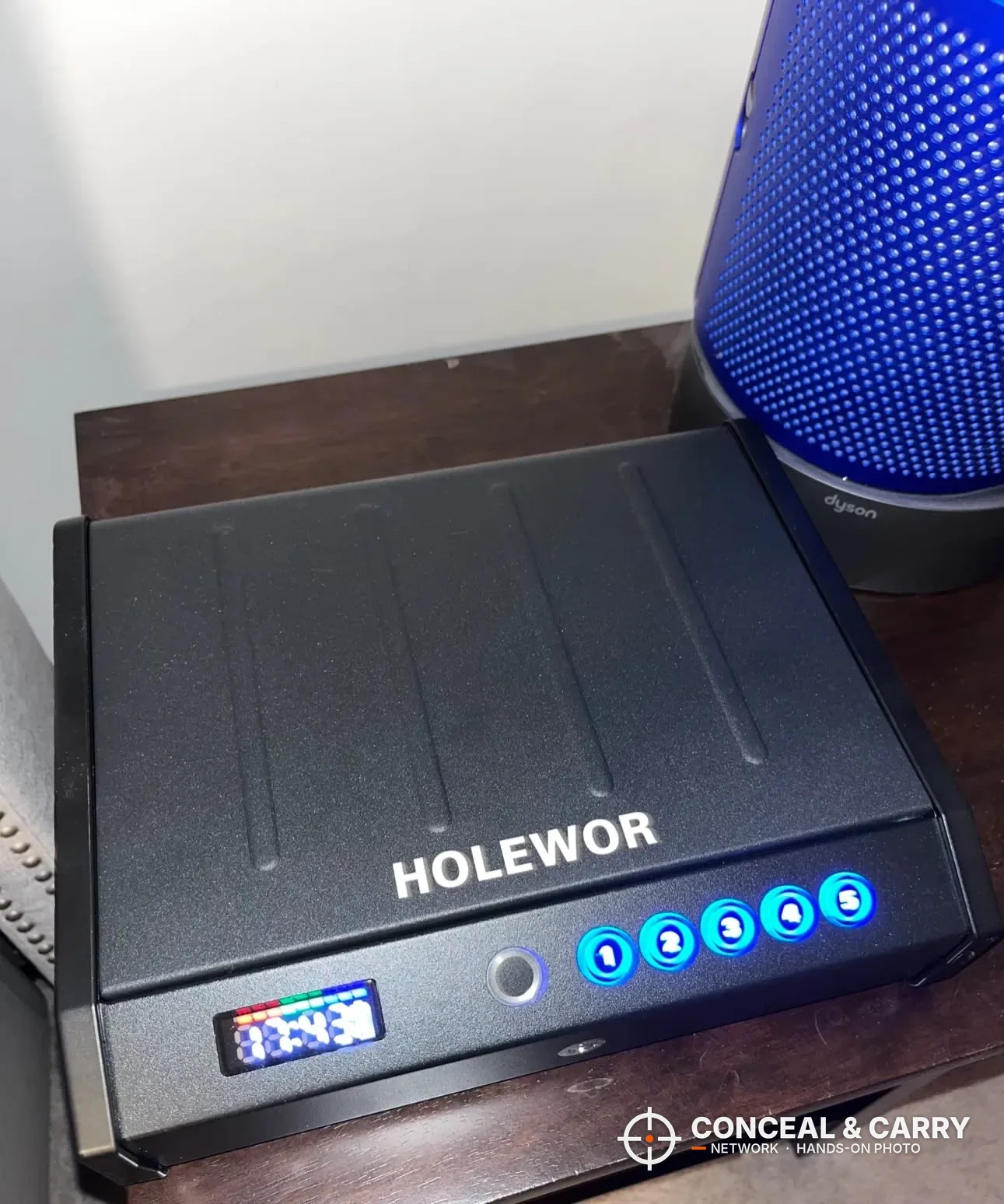 HOLEWOR handheld biometric safe closed on a nightstand with the display and buttons lit