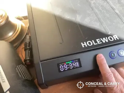Finger on the HOLEWOR handheld safe front panel beside the lit display