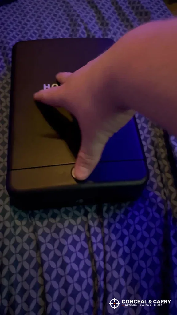 Hand reaching for the front edge of the HOLEWOR lock box in low light