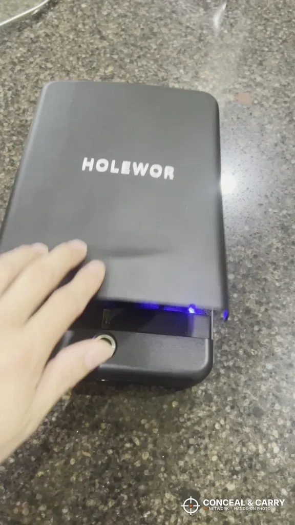 Hand on the closed HOLEWOR lock box with the blue light showing at the front