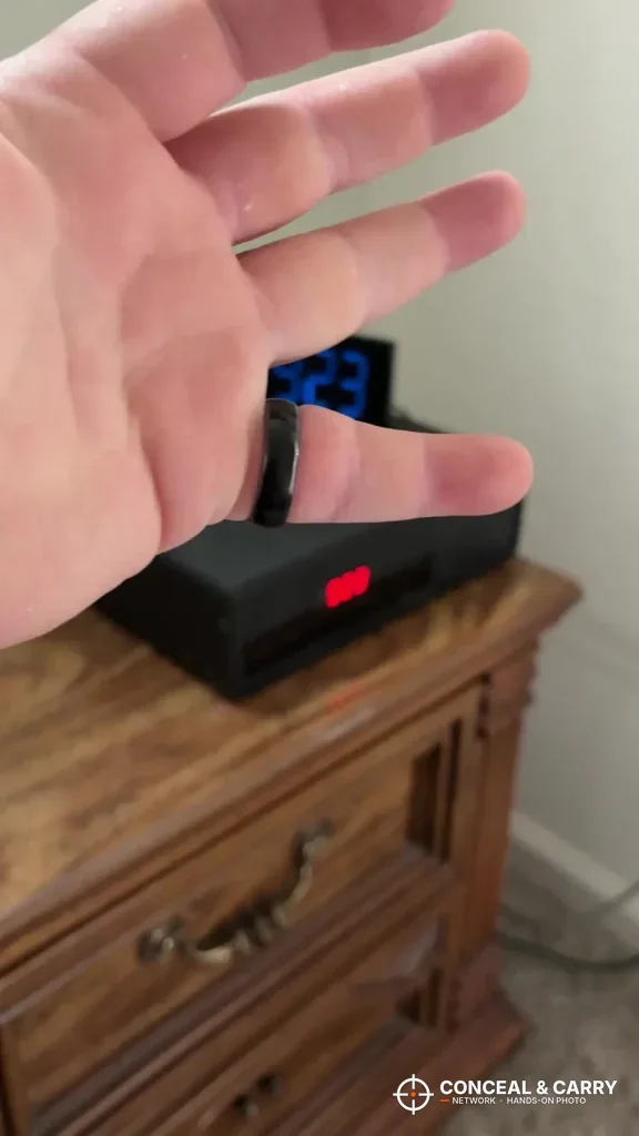 Hand held over the Hornady Night Guard on a wooden nightstand
