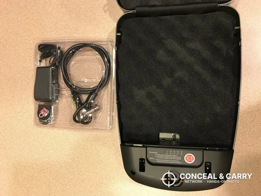 Hornady RAPiD Safe RFID open beside its power supply, security cable and tag in a bag