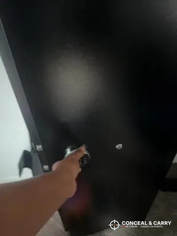Hand reaching for the lock on the INTERGREAT gun cabinet door
