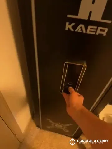 Hand reaching to open the KAER 13-16 gun safe in warm light