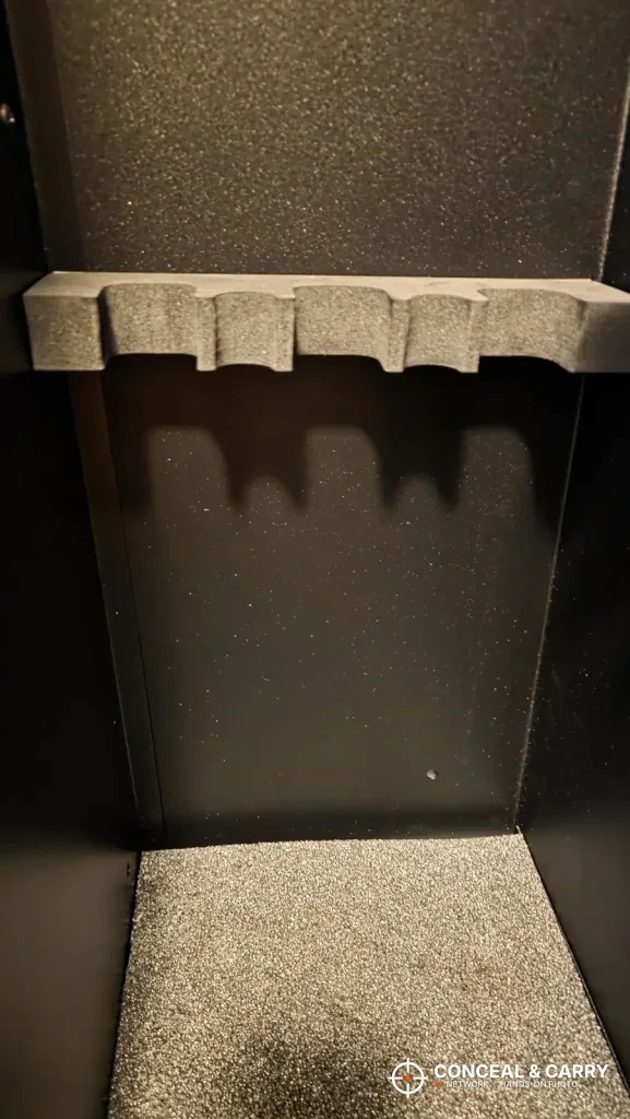 Lower section of a KAER 18-21 gun safe with a gray foam rack and carpeted floor