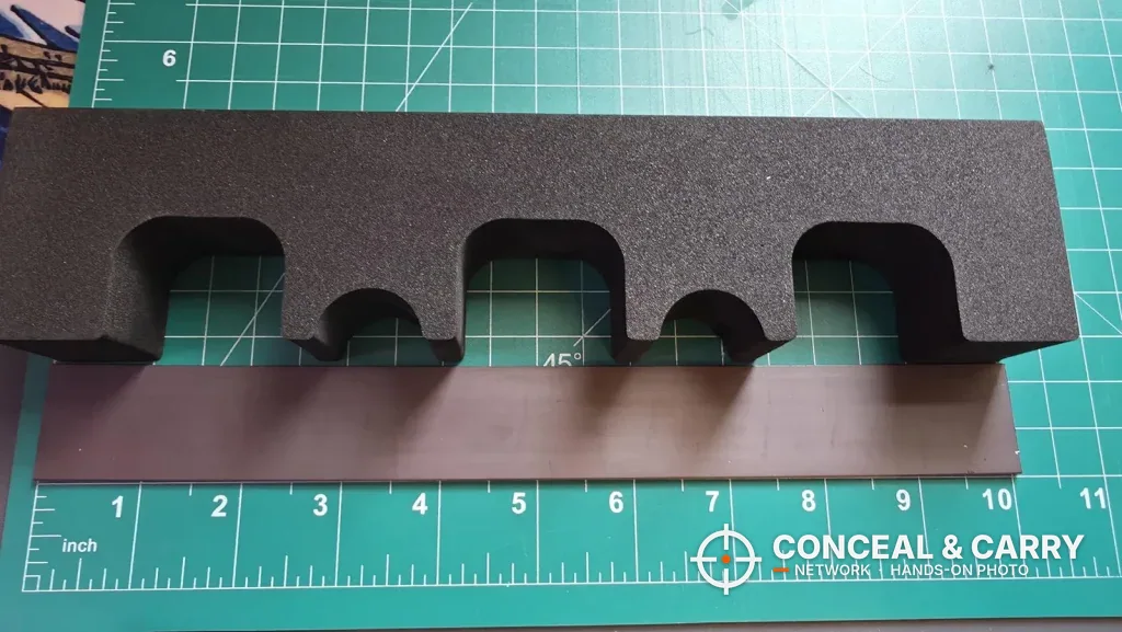 Black KAER 18-21 rifle rack laid on a cutting mat next to a ruler