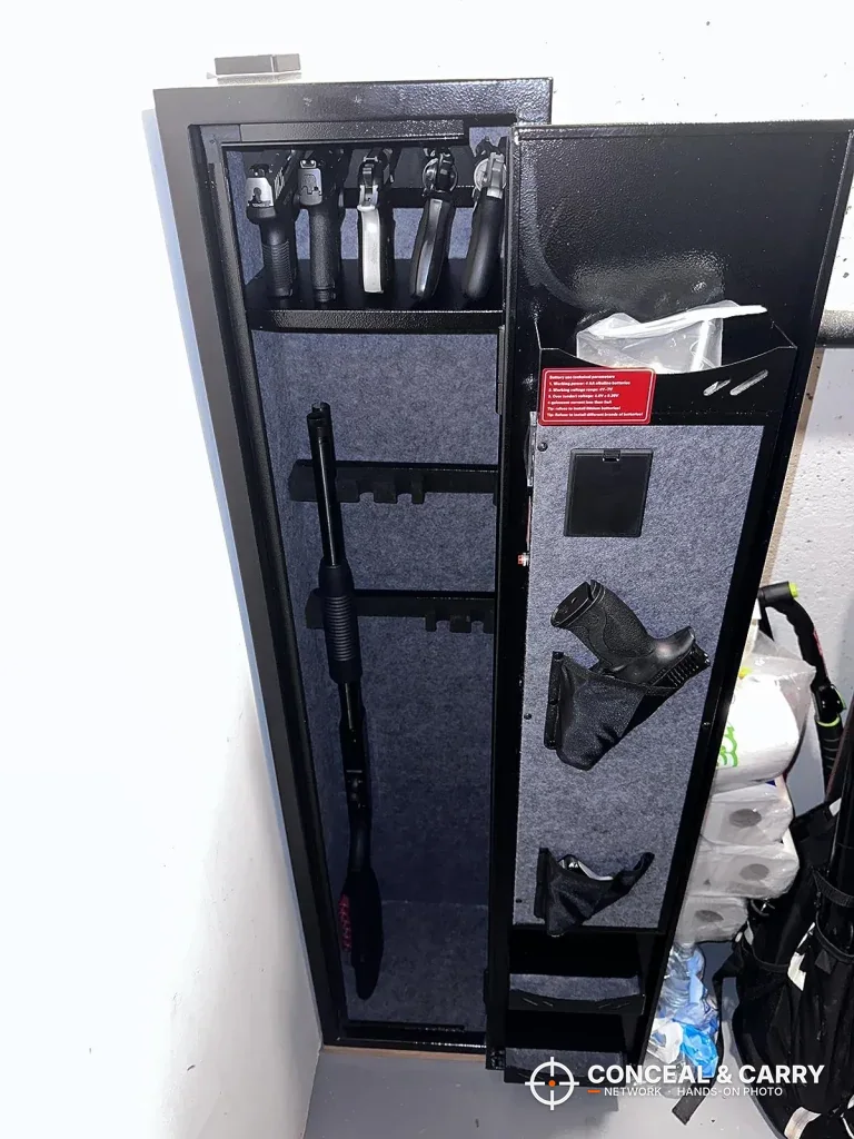 KAER 3-gun rifle safe open in a closet with a long gun in the rack and a handgun on the door