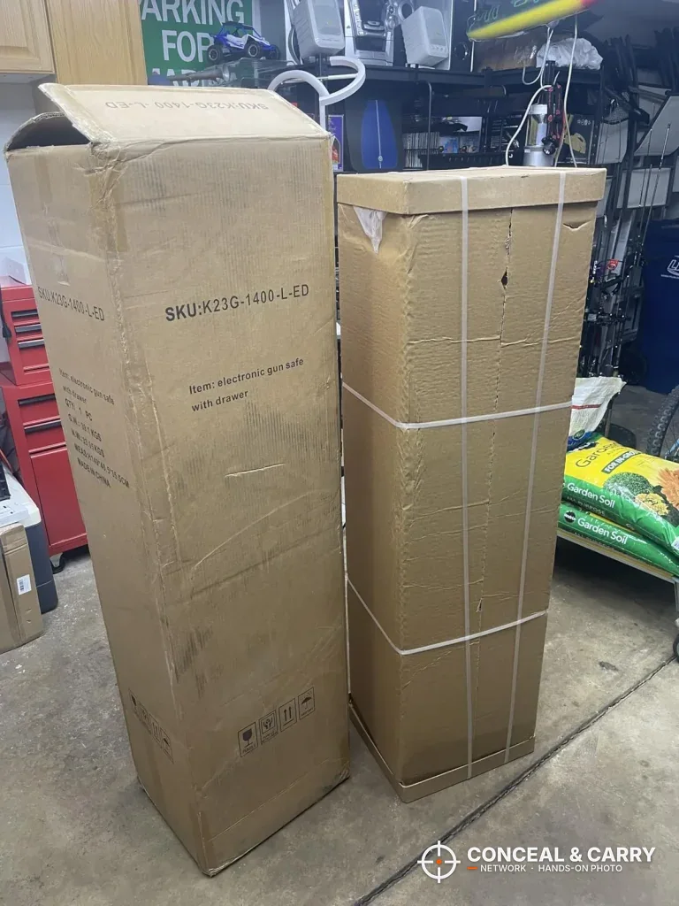 Two KAER 5-6 gun quick access safe shipping boxes standing in a garage