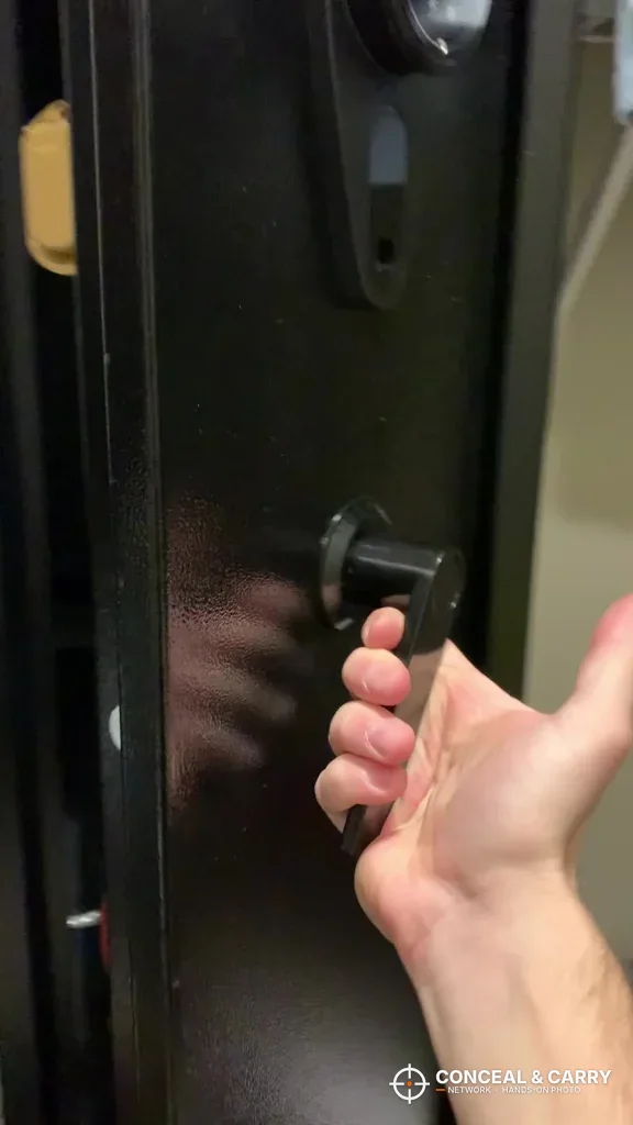 Hand turning the black handle on the KAER long gun safe door