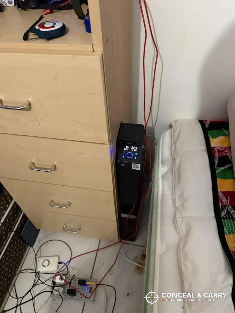 KornerBatl safe mounted between a dresser and the bed with the display lit