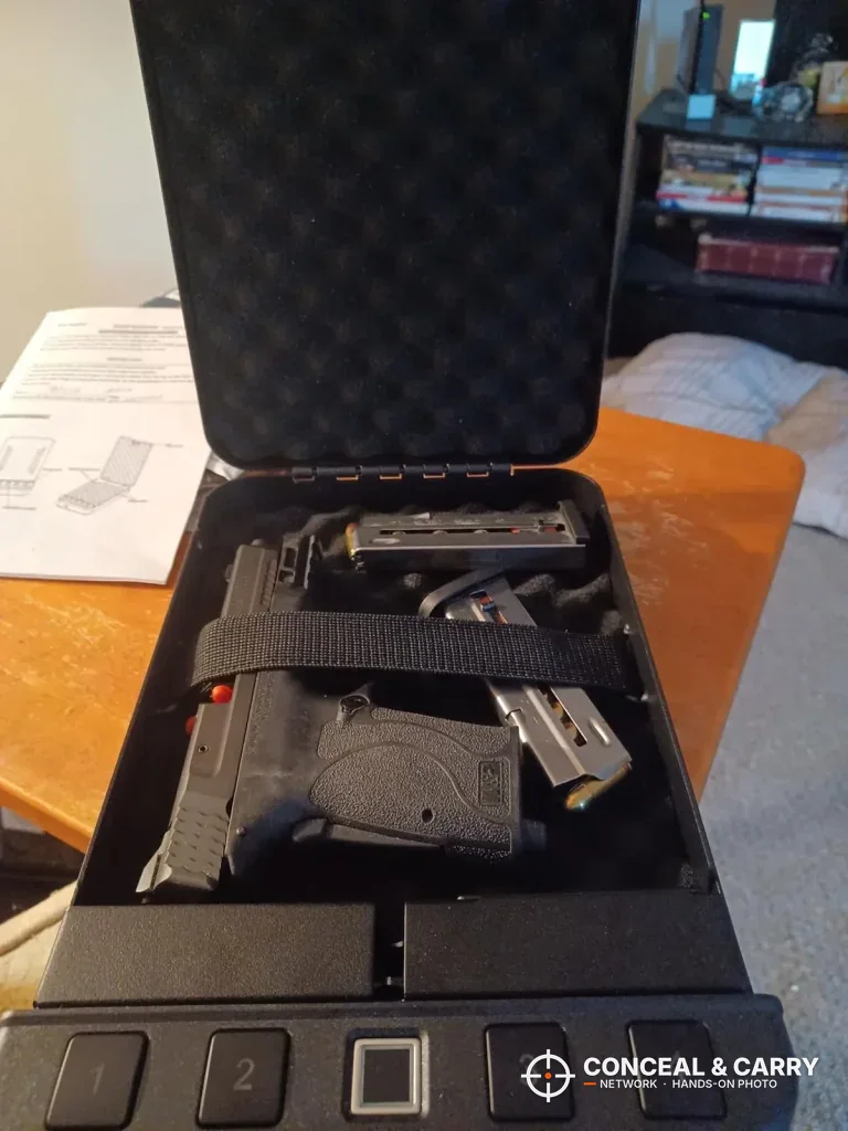 Langger biometric pistol lock box open with a pistol and two magazines under the strap